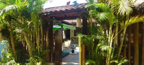a garden with palm trees and a wooden pergola at Pousada Horizonte dos Borbas in Abraão