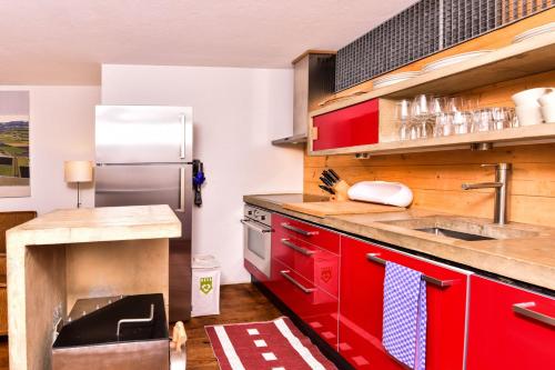 a kitchen with red cabinets and a stainless steel refrigerator at The Old Town Flat in Murten