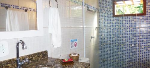 uma casa de banho com um lavatório e um chuveiro com azulejos azuis em Pousada Horizonte dos Borbas em Abraão