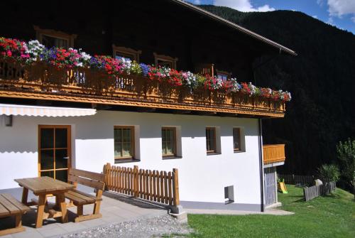 un edificio con un balcón con flores. en Ferienwohnungen Niederarnigerhof Familie Bauernfeind, en Kals am Großglockner
