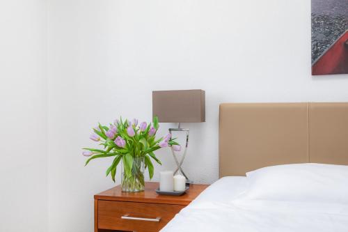 a vase of flowers on a table next to a bed at Swiss Star Aussersihl - Self Check-In in Zürich