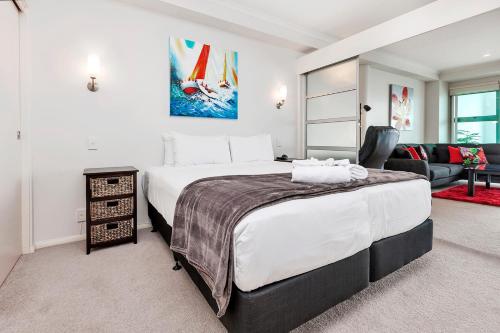 a bedroom with a large bed and a living room at QV Waterfront Magic Super Sunsets - 742 in Auckland