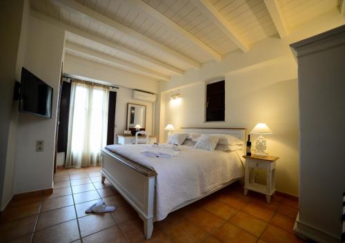 a bedroom with a large white bed and a window at Focalion Castle Luxury Suites in Pirgos Dhirou