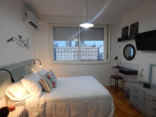 una camera da letto con un letto bianco e una finestra di Apio Studio Centro a Buenos Aires