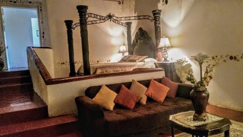 a bedroom with a bed and a couch with pillows at Hotel Spa Hacienda Real la Nogalera in Tequisquiapan