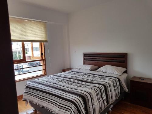 een slaapkamer met een groot bed en een gestreepte deken bij Jirón Tarapacá 398, La Punta - Callao in Lima