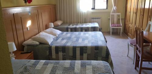 a room with three beds and a chair and a window at Hostal Brunete in Brunete