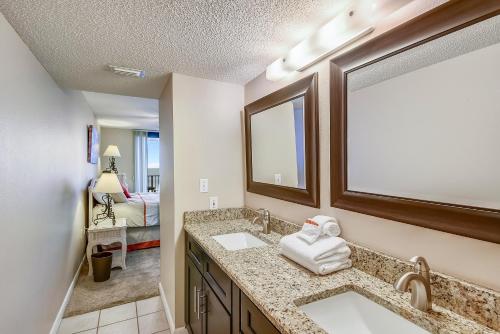 een badkamer met 2 wastafels en een spiegel en een slaapkamer bij Phoenix 6 Unit 504 in Orange Beach