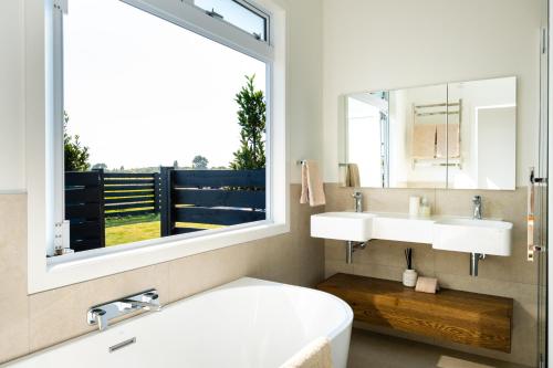 a bathroom with a tub and two sinks and a window at Lawn Road Retreat in Clive