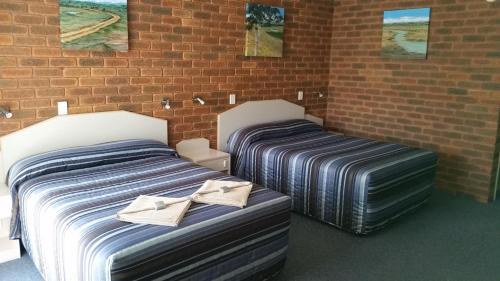 2 Betten neben einer Ziegelwand in der Unterkunft Yambil Inn in Griffith