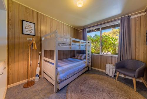 a bedroom with two bunk beds and a chair at INVERLOCH BEACH HUT - CLOSE TO BEACH AND SHOPS! in Inverloch
