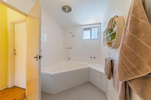 a white bathroom with a tub and a window at INVERLOCH BEACH HUT - CLOSE TO BEACH AND SHOPS! in Inverloch