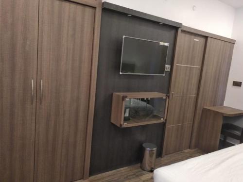 a bedroom with a tv and a wooden cabinet at Samsan Residentia in Visakhapatnam