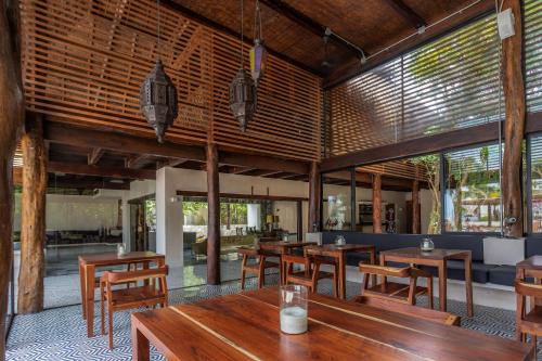 a restaurant with wooden tables and chairs and windows at Lotus Beach Hotel - Adults Only in Isla Mujeres