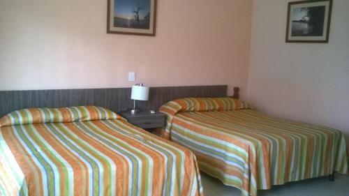 a hotel room with two beds and a lamp on a table at Hotel Playa Azul in Catemaco