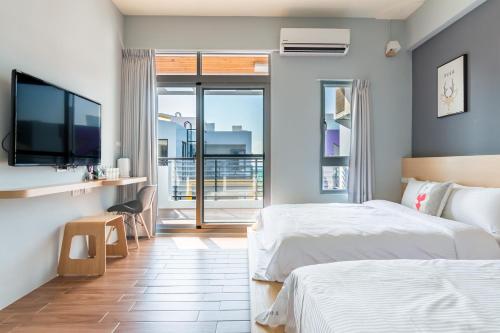 1 dormitorio con 2 camas y TV de pantalla plana en Penghu Clouds, en Magong