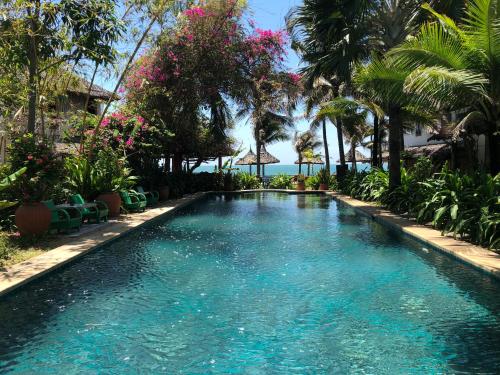a swimming pool in a resort with palm trees at Full Moon Beach Resort in Mui Ne