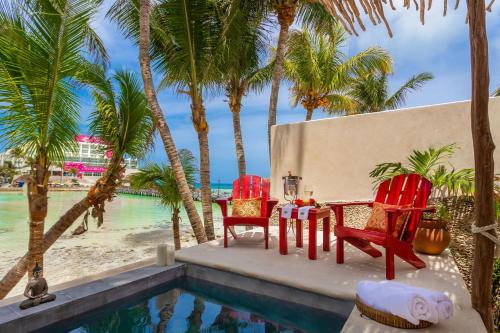 a table and chairs next to a pool with palm trees at Lotus Beach Hotel - Adults Only in Isla Mujeres
