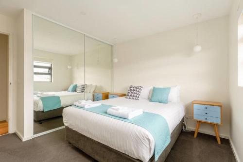 Kangaroo Bay Apartments في هوبارت: غرفة نوم بسريرين ومرآة