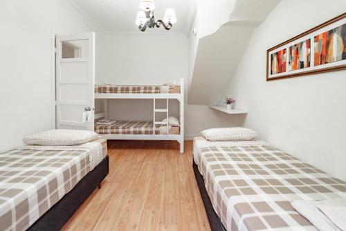 2 letti in una camera con pareti bianche e pavimenti in legno di Welcome to Pocitos a Montevideo
