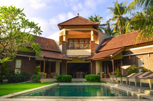 a house with a swimming pool in front of it at Villa Kelapa Candidasa in Candidasa