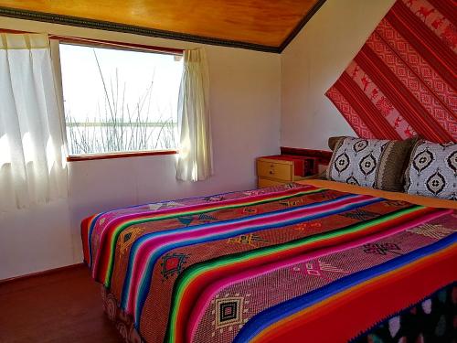 a bedroom with a colorful bed and a window at Uros Titicaca Khantaniwa Lodge in Puno