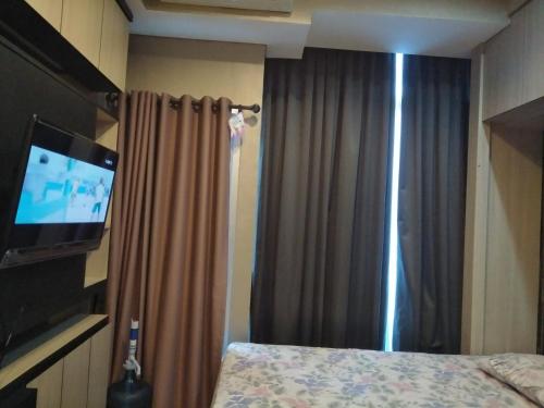 een slaapkamer met een bed en een flatscreen-tv bij Capitol Park Minimum Stay 2 Nights in Jakarta