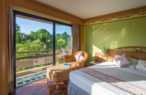 a bedroom with a bed and a large window at Maritime Park And Spa Resort in Krabi town