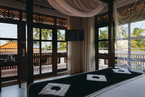 a bedroom with a bed with a view of a balcony at Amal Beach Hotel in Bentota