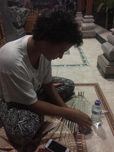 a woman sitting on the floor looking at a table at Pondok Intaran in Karangasem