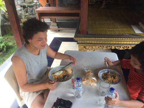 a man and two children sitting at a table eating food at Pondok Intaran in Karangasem