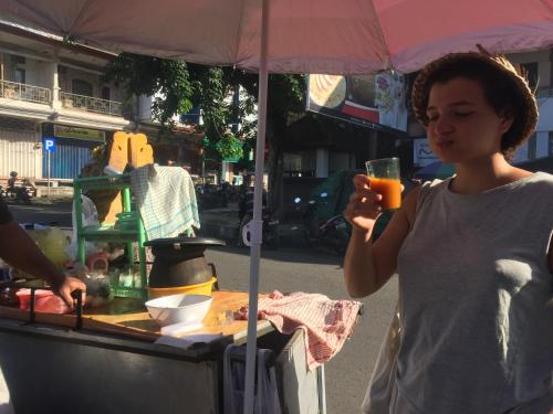 a woman holding a drink in front of a food cart at Pondok Intaran in Karangasem