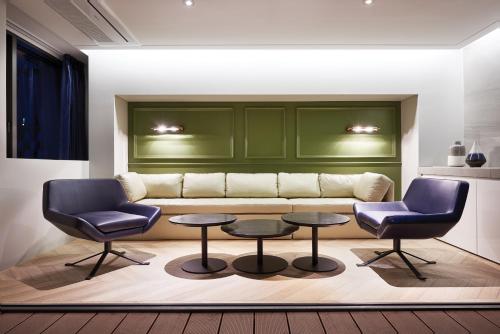 a living room with a couch and two chairs and tables at Hotel Peyto Samseong in Seoul