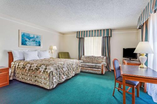 a hotel room with a bed and a desk and a desk at Days Inn by Wyndham Richmond/South in Richmond