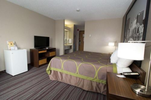 a hotel room with a bed and a flat screen tv at Super 8 by Wyndham Chicago O'Hare Airport in Elk Grove Village