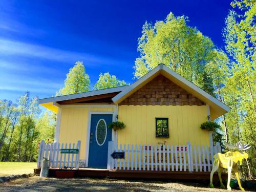 una pequeña casa amarilla con una puerta azul en Sunshine Cottage, en Talkeetna