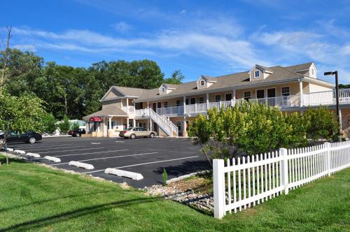a parking lot in front of a building with a white fence at At 9 Motel in Howell