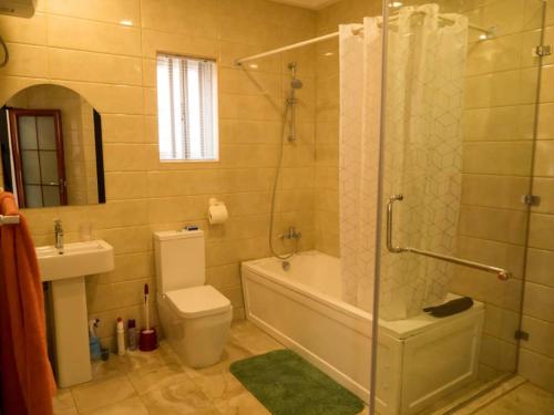 uma casa de banho com um chuveiro, um WC e um lavatório. em Zion Place em Ikeja