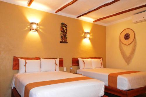 two beds in a bedroom with two lights on the wall at Hotel Casa San Juan in Valladolid