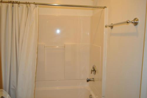 a bathroom with a shower with a white shower curtain at At 9 Motel in Howell