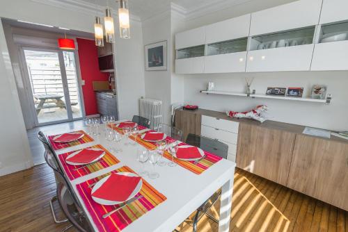 a kitchen with a table with red chairs and white cabinets at gite Brest Au Bout Du Ponton in Brest