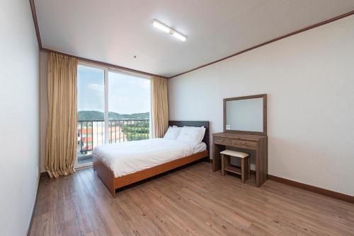 1 dormitorio con cama, espejo y ventana en Hyundai Soo Resort Sokcho, en Sokcho