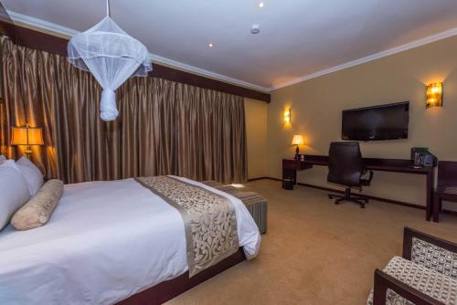 a hotel room with a bed and a desk and a television at Sunbird Capital in Lilongwe