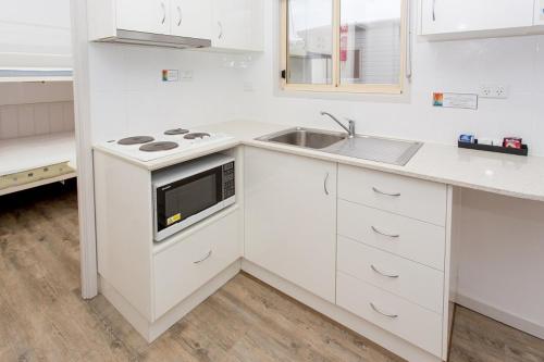 a white kitchen with a sink and a stove at Paradise Tourist Park in Tamworth