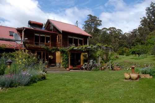 una casa de madera con patio y jardín en Birdwing Bed and Breakfast Weegena, en Weegena