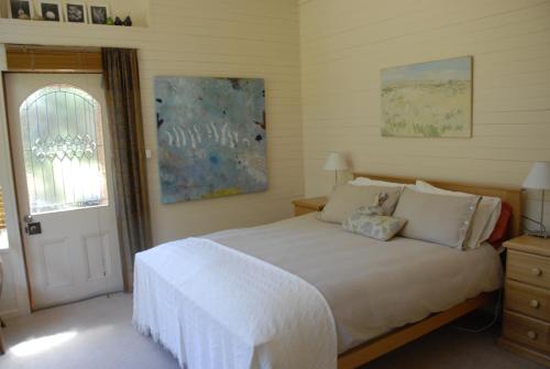 1 dormitorio con cama, ventana y puerta en Birdwing Bed and Breakfast Weegena, en Weegena