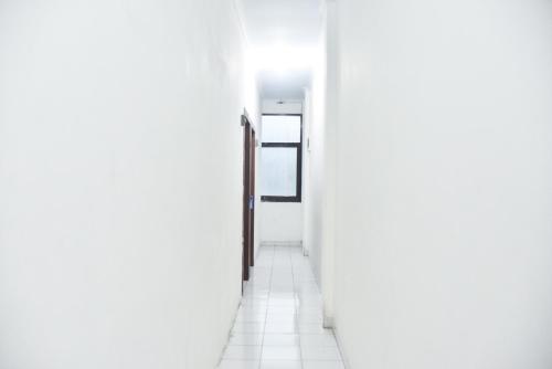 an empty corridor with a door in a white hallway at RedDoorz at Pettarani Square Makassar in Makassar