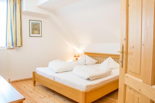Schlafzimmer mit einem Bett mit weißer Bettwäsche und Kissen in der Unterkunft Appartement Schizentrum Grosseck - Speiereck in Mauterndorf