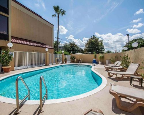 a swimming pool with chairs and a building at Comfort Inn & Suites Lantana - West Palm Beach South in Lantana