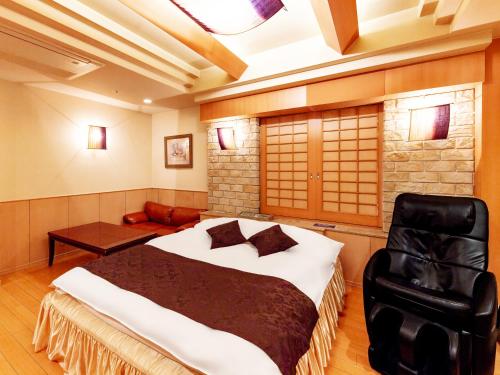 a bedroom with a large bed and a chair at Hotel Mine (Love Hotel) in Kurume
